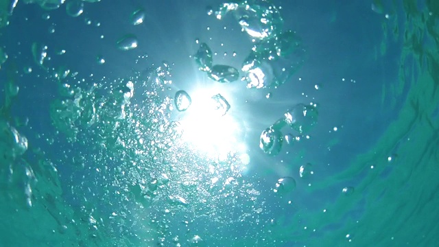 自下而上:气泡漂浮在平静的海洋表面。视频素材