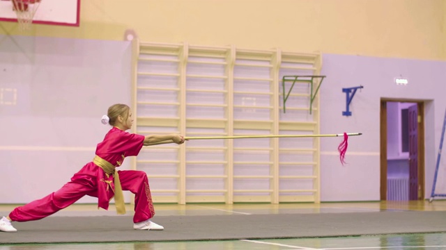 年轻的女孩穿着红色的义夫服做着千步式练习中国功夫太极。视频下载