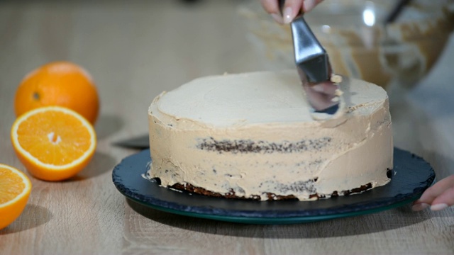 糖果师傅把奶油放在蛋糕上面。面包师用奶油糖霜使蛋糕光滑。视频素材