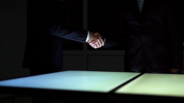 两人在屏幕前握手。慢动作视频下载