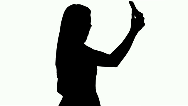 一个年轻美丽的女人在她的手机上自拍视频下载