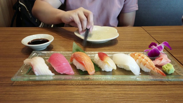 一名妇女在日本料理餐厅用筷子挑选寿司。视频素材