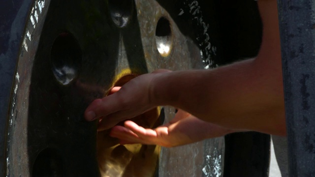 一名男子的手摸着佛寺里的钟。视频素材