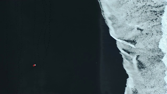 冰岛黑沙滩上女人的鸟瞰图视频素材