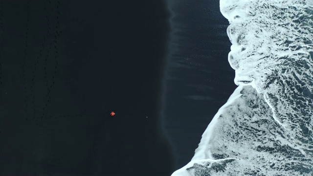 冰岛黑沙滩上女人的鸟瞰图视频下载