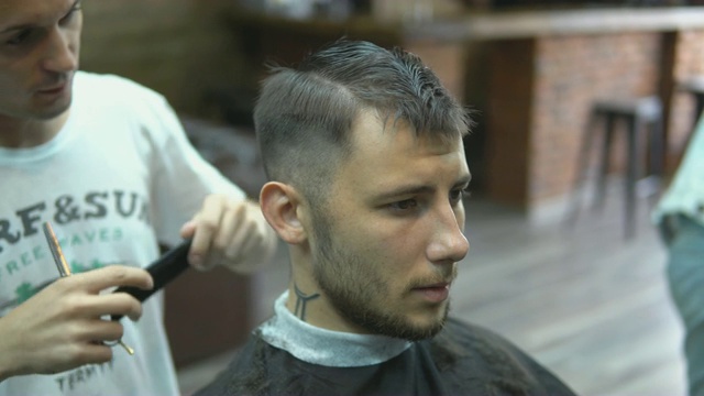 特写大师在理发店里为男人理发和刮胡子，美发师为年轻人做发型视频下载