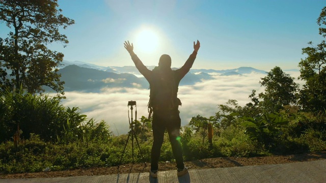 空中男性摄影师站在山上，举起他的手在早晨的日出视频下载