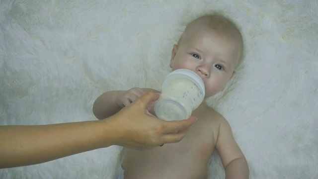 母亲用手缓慢地用奶瓶喂刚出生的婴儿。视频素材