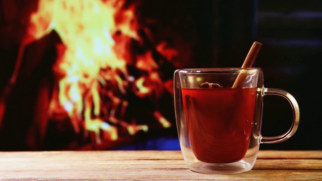 特写杯与热葡萄酒在一张木桌和壁炉里的火视频素材
