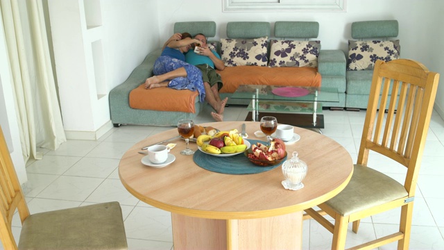 男人和女人躺在沙发上吃水果，用智能手机自拍视频素材