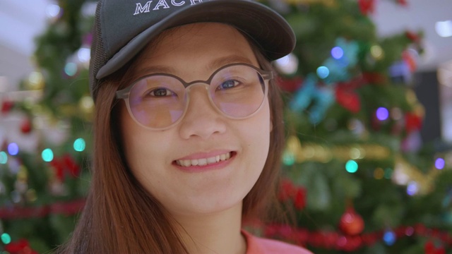 亚洲妇女的肖像看着相机和微笑。圣诞树的背景。概念:度假、享受、度假。视频素材
