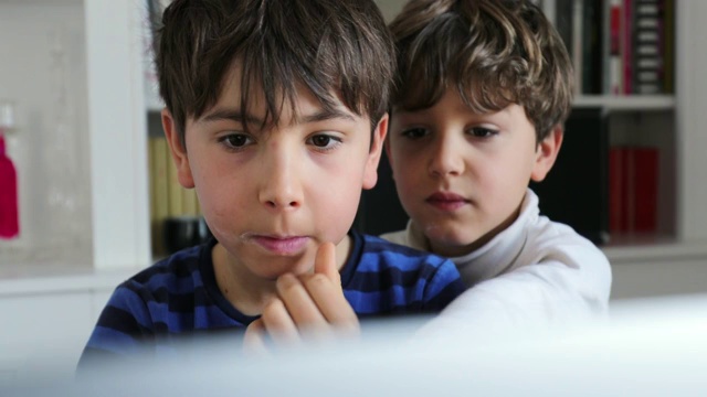 孩子们早上坐在电脑屏幕前。孩子们上网在网上寻找媒体视频素材