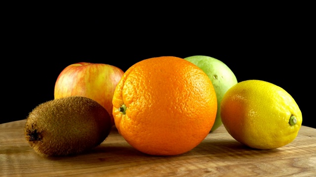 猕猴桃，苹果和橘子在黑色的背景。切菜板在运动。视频下载