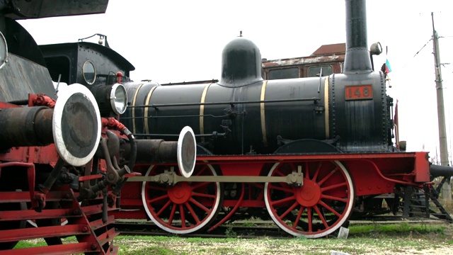一个老的和生锈的蒸汽机车的特写与车厢在一个火车站的条件很差视频素材