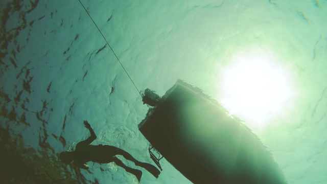 水下拍摄的人游泳潜水与鳍和面具下的船浮动。视频素材