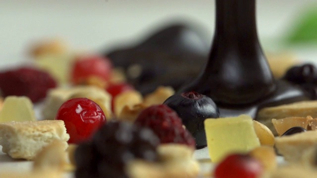 融化的巧克力在榛子和红色水果高清视频视频素材