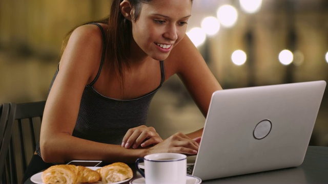 一个愉快的白人女人，一边喝着咖啡，一边用着笔记本电脑视频素材