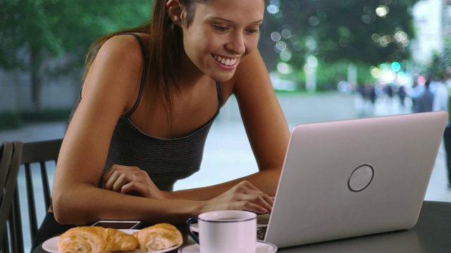 快乐的女性一边在外面用笔记本电脑工作一边享受咖啡视频素材