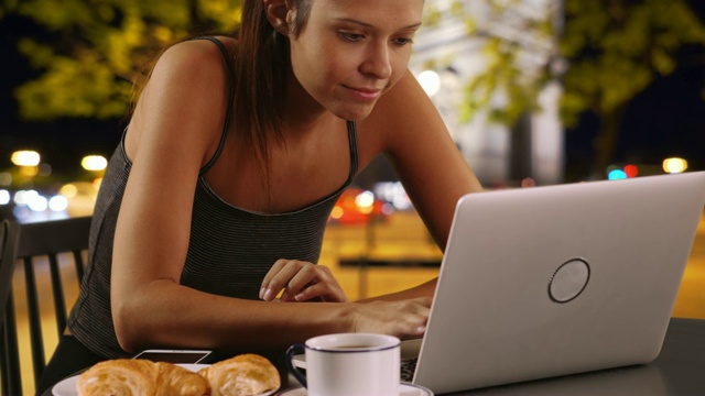 巴黎的女游客，晚上一边喝咖啡一边浏览笔记本电脑视频素材