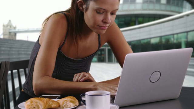 女游客坐在塔桥附近用笔记本电脑工作和喝咖啡视频素材