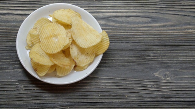 薯片炸酥脆碟放在木桌上，小吃开胃，美味可口却不健康，动来动去。视频素材