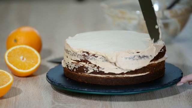 糖果师傅把奶油放在蛋糕上面。面包师用奶油糖霜使蛋糕光滑。视频素材