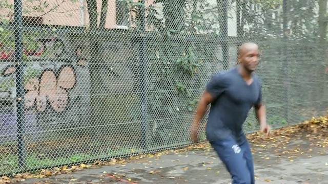 年轻的男运动员对着篱笆踢足球视频下载