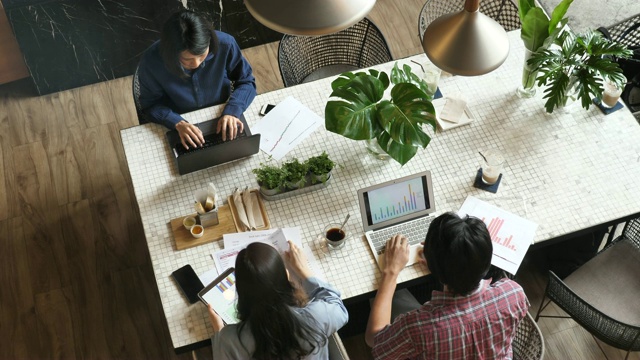 在时髦的共享办公空间中，商业人士在会议室会议桌上使用图表和大数据讨论财务报告的俯视图视频素材