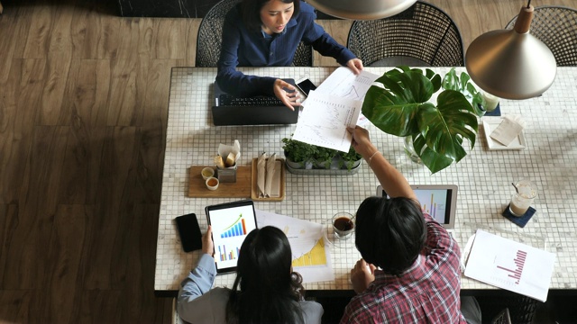 在时髦的共享办公空间中，商业人士在会议室会议桌上使用图表和大数据讨论财务报告的俯视图视频素材
