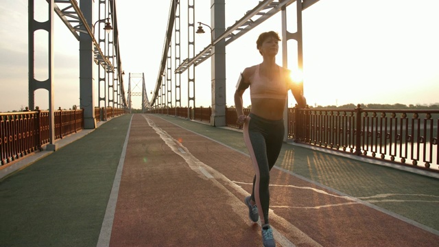 高级女运动员日出时在桥上跑步视频素材