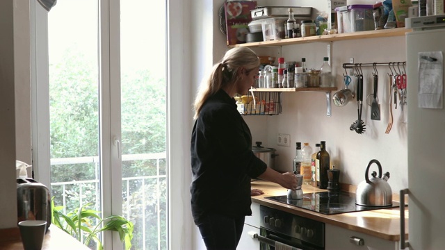 手持拍摄的中年妇女在厨房煮咖啡壶视频下载