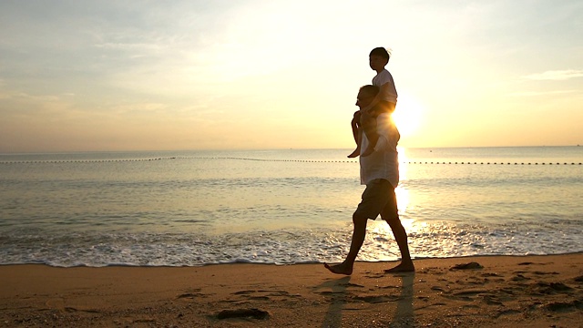 日出时，父亲和儿子在海滩上玩耍，他们一起度过了高质量的家庭时光。视频素材