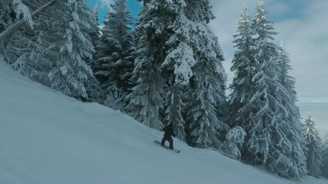 一个穿着黑色衣服，背着背包的年轻人骑着滑雪板高速下山视频素材