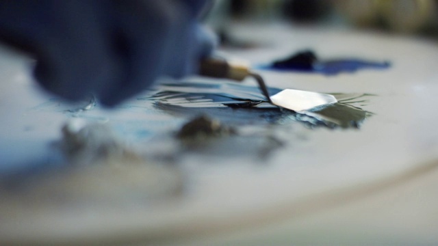 一个艺术家戴着防护手套在画布上用调色板刀涂抹油画颜料的特写镜头视频下载