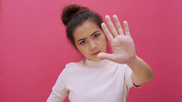 严肃的女人挥舞手指，没有手势，看着相机孤立的粉红色背景4k视频素材