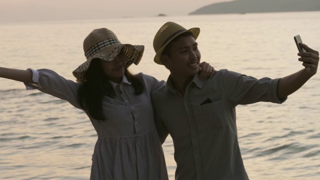 亚洲情侣在海边用智能手机合影。视频素材