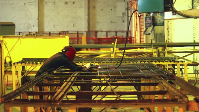 工人在防护面罩下焊接钢结构。重工业工人视频下载