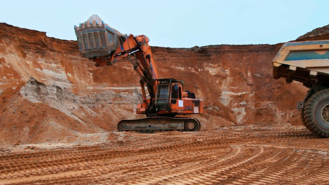挖掘机将沙子装进自卸卡车。履带式挖掘机挖土视频素材
