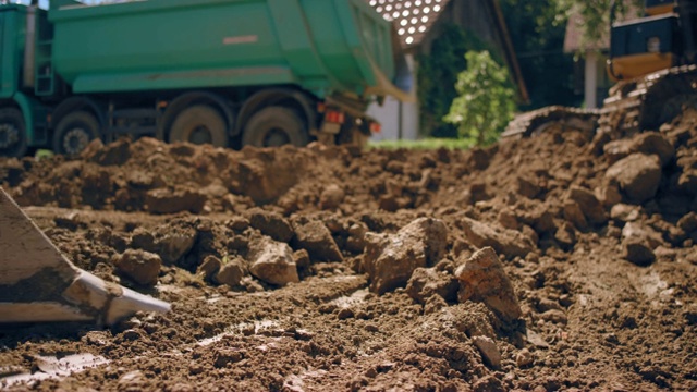 SLO MO挖掘机铲斗在阳光充足的施工现场捡拾上层土壤视频下载