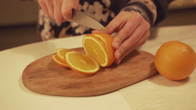 女性手在砧板上切橘子，准备自制的热红酒，配上橘子片，蔓越莓，肉桂。视频素材