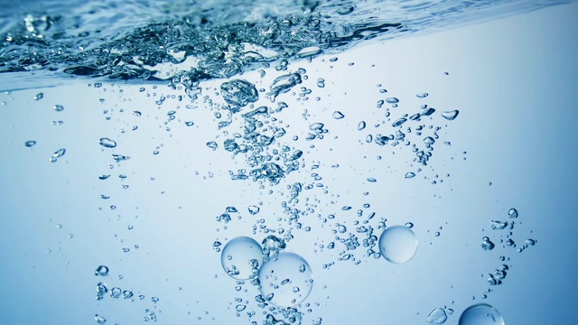 慢镜头拉近了多个清晰的球体落入水中，并在水下产生各种大小的气泡视频素材