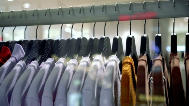在百货公司，购物中心和服装概念的时尚服装店挂衣架和衣架上的扶手4k镜头的场景视频下载