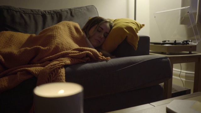 一个女人晚上睡在沙发上听着唱片视频下载