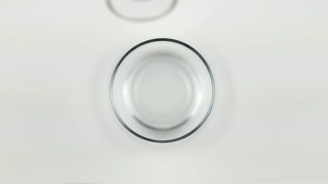 顶视图倒牛奶到一个白色的背景上的玻璃杯视频素材