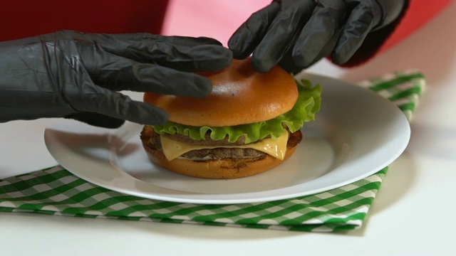 戴黑手套的人吃高热量的快餐汉堡，暴饮暴食视频素材
