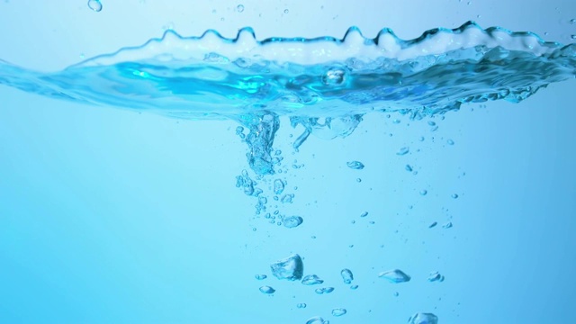 慢镜头拉近了两个冰块落入水中，在水下产生各种大小的气泡视频素材