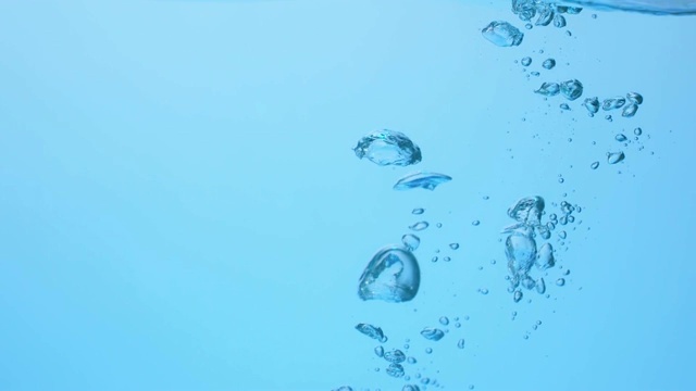 慢镜头拉近了一个冰块落入波浪中，在水下产生各种大小的气泡视频素材