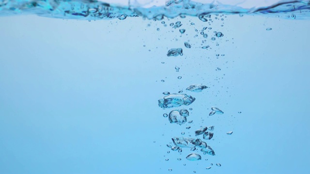 慢镜头拉近了两个冰块落入波浪中，在水下产生各种大小的气泡视频素材
