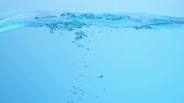 慢镜头拉近了一个冰块落入波浪中，在水下产生各种大小的气泡视频素材