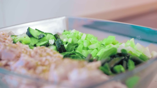 特写，慢镜头，生菜在一个玻璃沙拉碗鸡肉和绿色植物填满芝麻酱。素食主义的概念，自制饮食和纯素视频素材